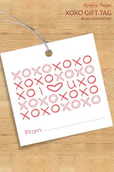 an xoxo gift tag is hanging on a wooden table with a string attached to it