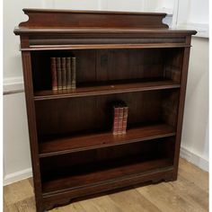 a bookcase with two books on top of it and some other items in the bottom shelf