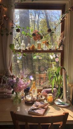 a wooden table topped with vases filled with flowers next to a window covered in greenery