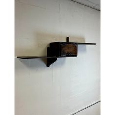 a wooden shelf mounted to the side of a white wall next to a metal bar