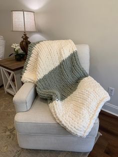 a couch with a blanket sitting on top of it next to a table and lamp