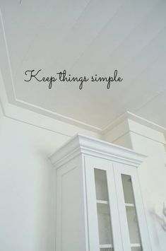 there is a white cabinet with writing on the wall above it that says keep things simple