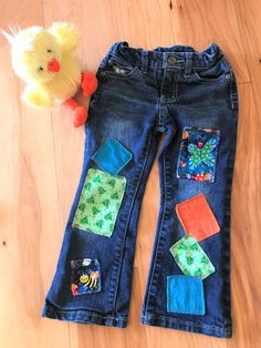 a pair of blue jeans with patches on them next to a stuffed animal and toy duck