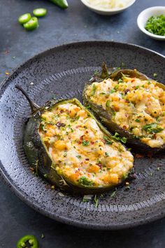 two stuffed peppers on a black plate