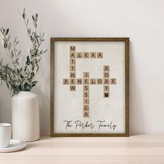 a cross made out of scrabble tiles sits next to a cup and vase