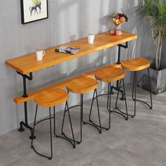 three stools and a table in front of a potted plant on the wall