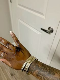 a woman's hand with tattoos and rings on it