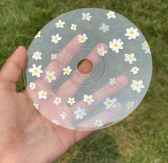 a hand holding a clear disc with white and yellow flowers on the inside of it