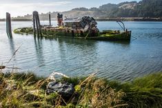 an old boat sitting on top of a body of water next to a shore line