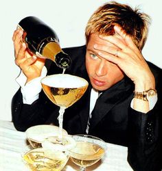 a man in a tuxedo pours a glass of white wine into a goblet