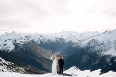 a bride and groom standing on top of a snow covered mountain