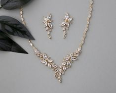 This bridal necklace set is a lovely design of varying sizes of marquise leaf shaped jewels and is a great selection for any bridal style. The necklace is 16.25 inches long with a 1 inch drop, and the earrings are about 1.25 inches long with post pierced backs. Grade AAA CZ, rhodium, gold, or rose gold plated, lead and nickel free. Gold Leaf-shaped Jewelry For Wedding, Leaf-shaped Gold Jewelry For Wedding, Gold Marquise Cut Wedding Jewelry, Marquise Cut Crystal Jewelry For Wedding, Gold Bridal Hair Accessories, Bridal Necklace Set, Gold Necklace Set, Bridal Necklace, Bridal Hair Accessories