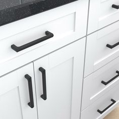 a kitchen with white cabinets and black counter tops