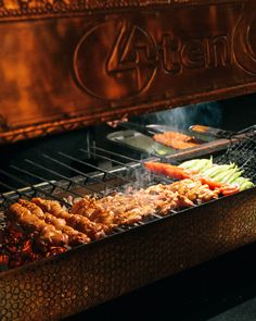 an open grill with meat and vegetables cooking on it