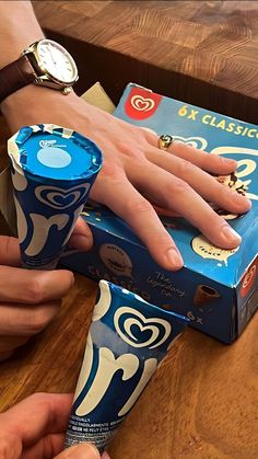 a person is holding an ice cream cone in front of a box on a table