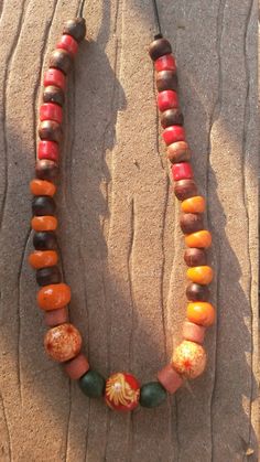 This slip-on, warm tone, wood bead necklace has a hippy feel to it.  It is made with mostly repurposed beads strung on a waxed black cord.  There are three accent beads, two of which have a red and cream floral pattern, the third of which has a dramatic red, cream, and orange stylized flower pattern. Cheap Orange Necklaces With Wooden Beads, Adjustable Rustic Brown Beaded Necklaces, Orange Wooden Beaded Necklaces For Beach, Orange Wooden Beads For Festival, Orange Wooden Beads For Festivals, Large Brown Beads For Festival, Brown Wooden Beaded Necklaces For Festivals, Hippie Brown Necklace With Colorful Beads, Natural Wooden Beaded Necklaces For Festival