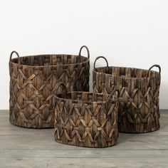 three woven baskets sitting on top of a wooden table next to each other with handles