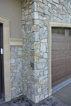 two brown garage doors are on the side of a stone building that is made out of stones