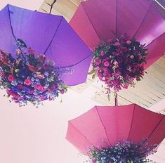 three purple and pink umbrellas with flowers hanging from the ceiling in front of them