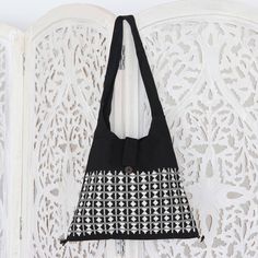 White diamonds seem to shimmer on a background of black cotton. Created by UMBVS Desert Weavers of India this dazzling handbag emulates fine hand embroidery with its complex and ornate weaves. The delightful sling tote is fully lined. Inside a zipper pocket keeps things organized while tassels and sheesham wood beads adorn each corner. Black Embroidered Rectangular Shoulder Bag, Black Embroidered Tote Shoulder Bag, Embroidered Black Hobo Bag For Daily Use, Black Embroidered Hobo Bag, Black Embroidered Hobo Bag For Daily Use, Embroidered Black Satchel Shoulder Bag, Traditional Black Bag For Everyday Use, Black Embroidered Canvas Tote Bag, Embroidered Black Bag For Everyday Use