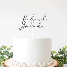 a white cake topped with a wooden slice and the words richard and anada on it