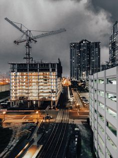 the city is lit up at night and there are buildings under construction in the foreground