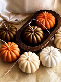 small pumpkins are sitting in a wooden tray on a table next to some string