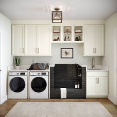 a washer and dryer in a small room with white cupboards on the wall