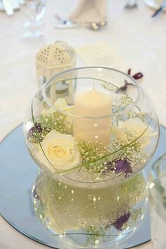 a glass bowl filled with flowers and candles