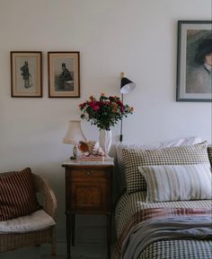 a bed room with a neatly made bed next to a chair and a vase filled with flowers