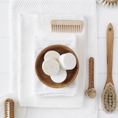 an overhead view of a wooden bowl with soap, brush and combs on it