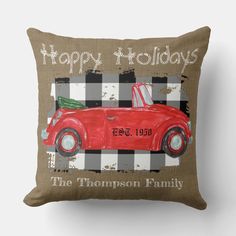 a red car with a christmas tree on the hood is sitting in front of a plaid pillow