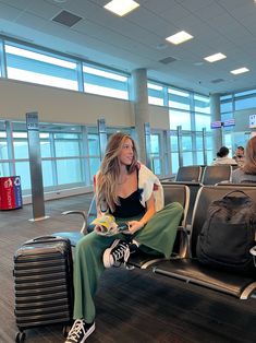 a woman sitting on top of an airport bench