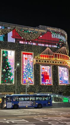 a bus is parked in front of a building decorated with christmas lights