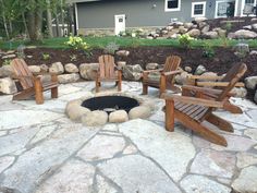 an outdoor fire pit surrounded by wooden chairs