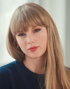 a close up of a person with long hair and blue eyes wearing a black sweater