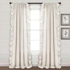 white curtains with ruffles hanging on the window sill in front of two framed pictures