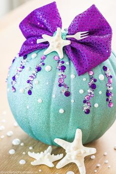 a blue pumpkin decorated with purple glitter and a starfish on the side sitting on a table