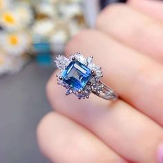 a woman's hand holding an engagement ring with blue and white stones on it