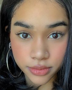 a close up of a person with large hoop earrings on her head and blue eyes