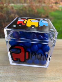 a clear box filled with blue balls sitting on top of a wooden table