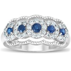 a white gold ring with blue and white diamonds on the sides, surrounded by round cut stones