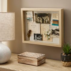 a wooden box sitting on top of a table next to a lamp and a vase