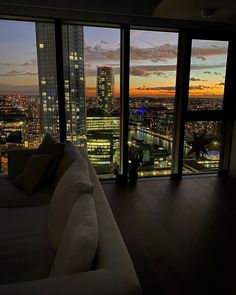 a living room filled with furniture and large windows overlooking the city at sunset or dawn