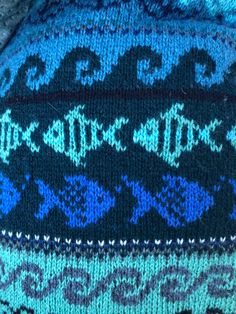 a blue and black knitted hat with designs on it