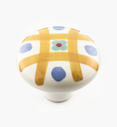 a close up of a ceramic object on a white surface with blue and yellow dots