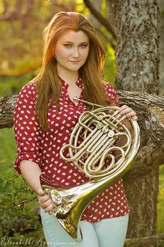 a woman holding a french horn in her hands