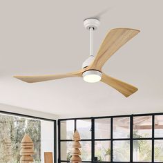 a ceiling fan in a living room with windows and plants on the table next to it