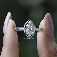 a woman's hand holding an engagement ring with a diamond in the middle and side