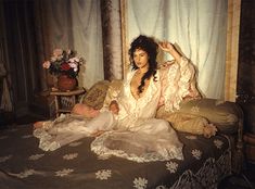 a woman sitting on top of a couch next to a vase with flowers in it